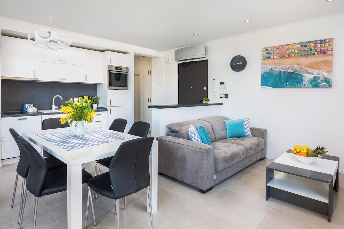 A modern apartment with a dining area, kitchen, living room, and a large window.