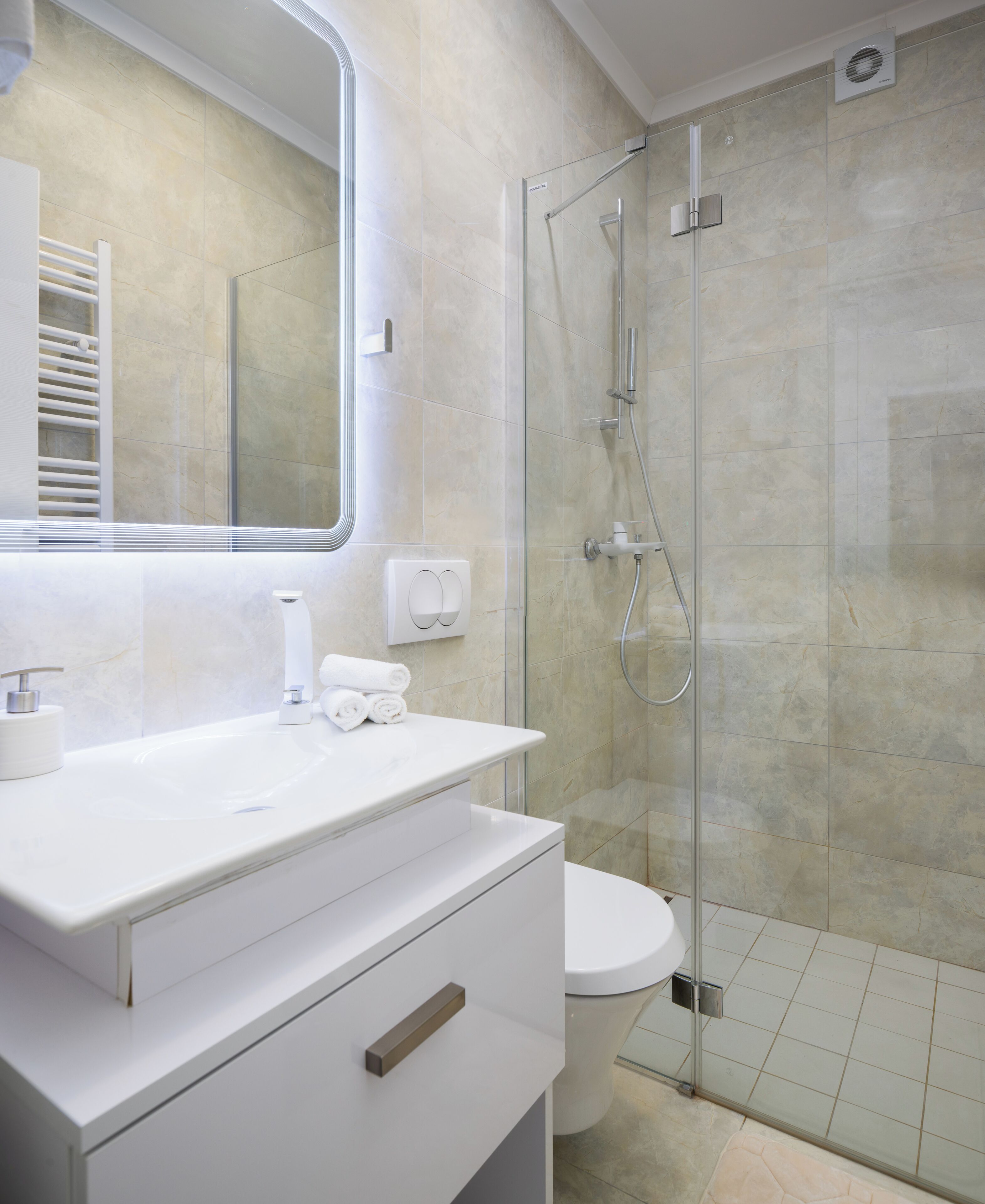 A modern bathroom with a glass-enclosed shower, a white sink, and a toilet.