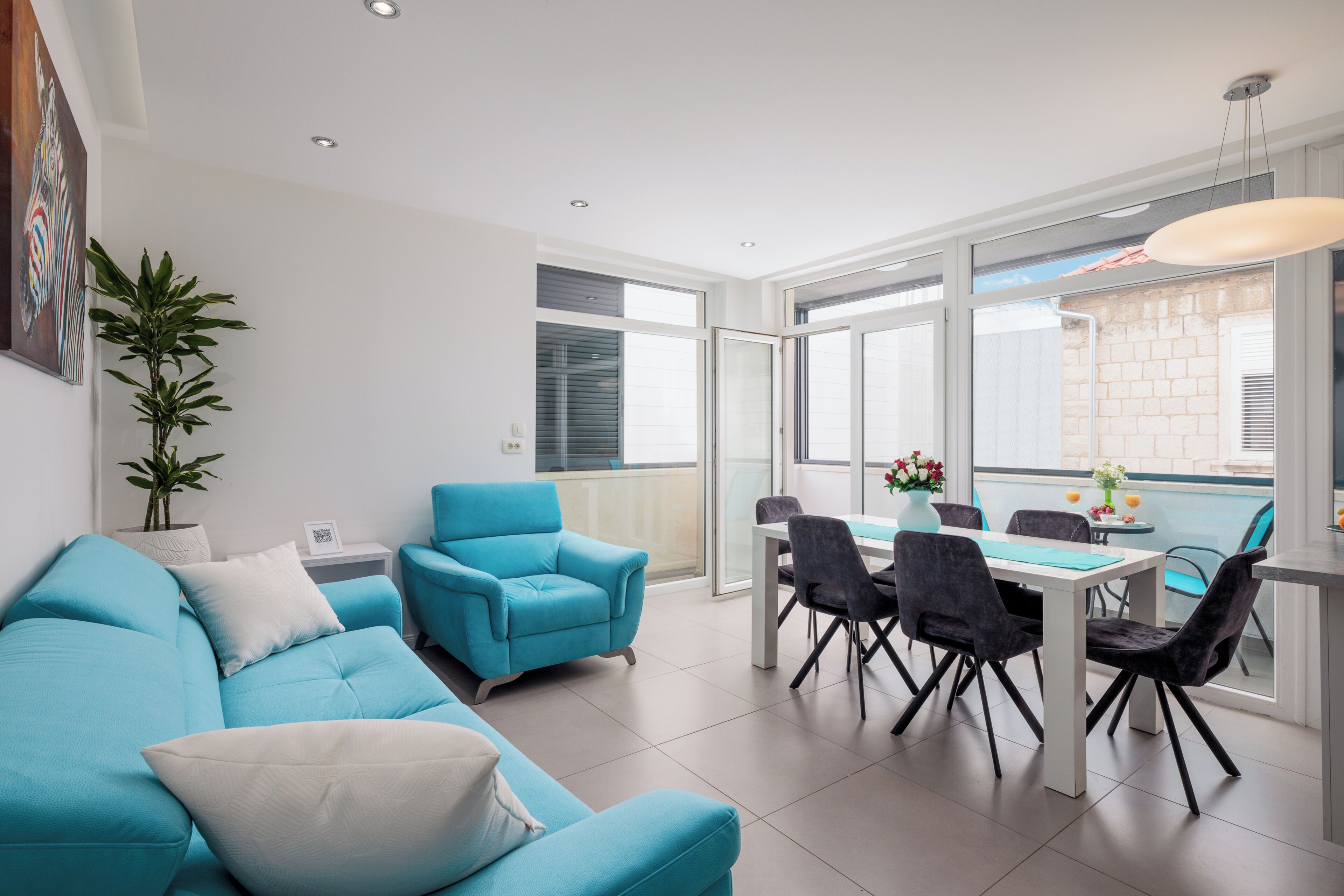 Ein modernes Wohnzimmer mit einer Couch, Sesseln, einem Esstisch und einem Balkon mit Blick.