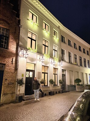 Ein Gebäude mit vielen Fenstern, einer Ziegel-Fassade und einem gepflasterten Eingangsbereich.