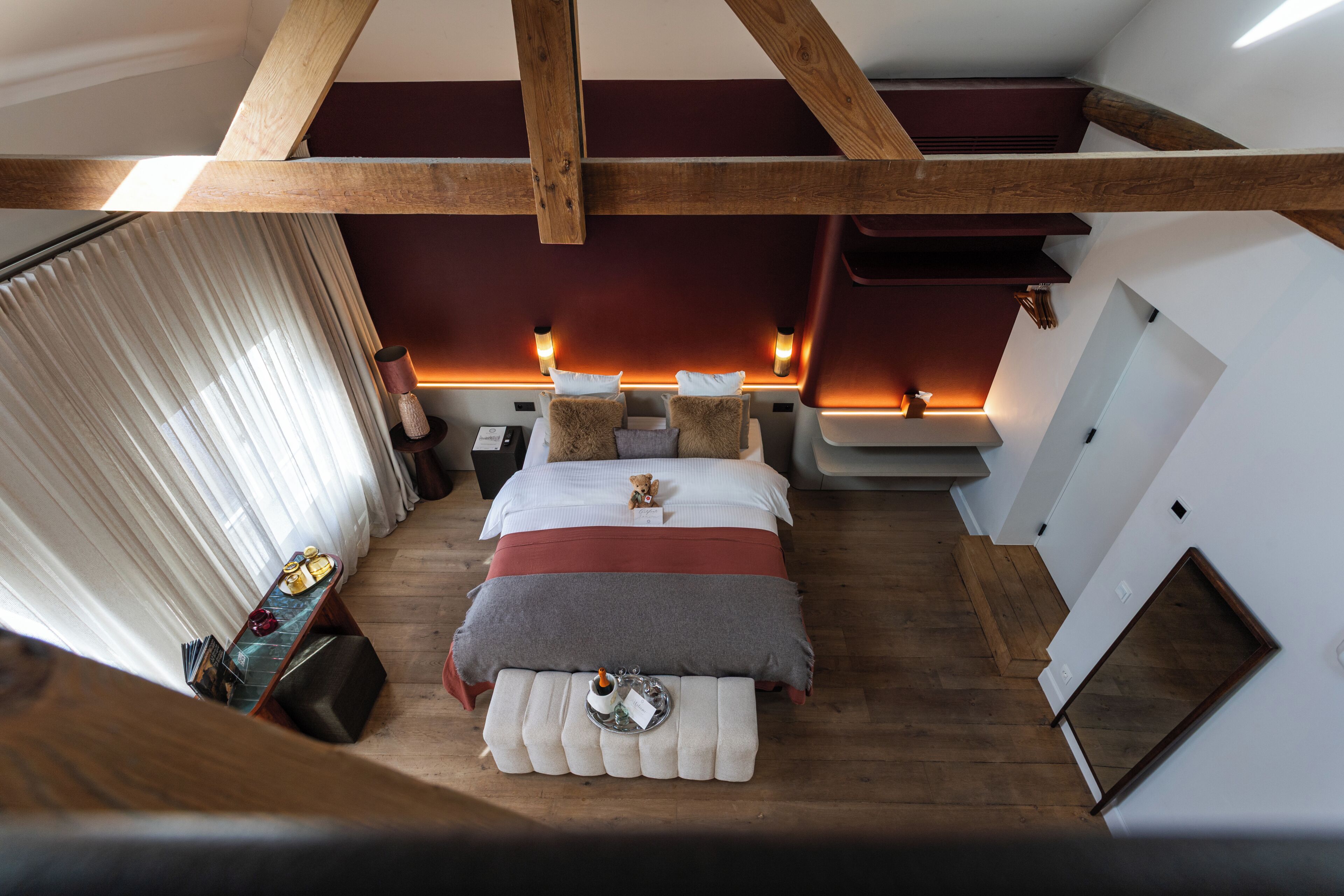 Un dormitorio con una cama, mesitas de noche, una ventana con cortinas y techo de madera.