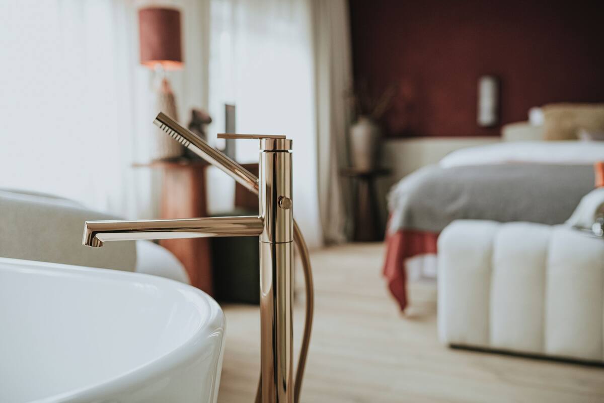 Un baño moderno con un grifo metálico elegante y una bañera blanca.