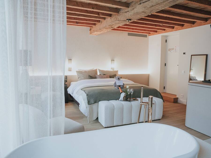 Ein modernes Schlafzimmer mit einem großen Bett, Nachttischen, einem Schminktisch und einer Badewanne.