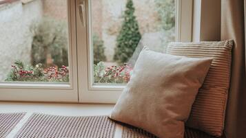 A window with a view of a brick wall and greenery outside.