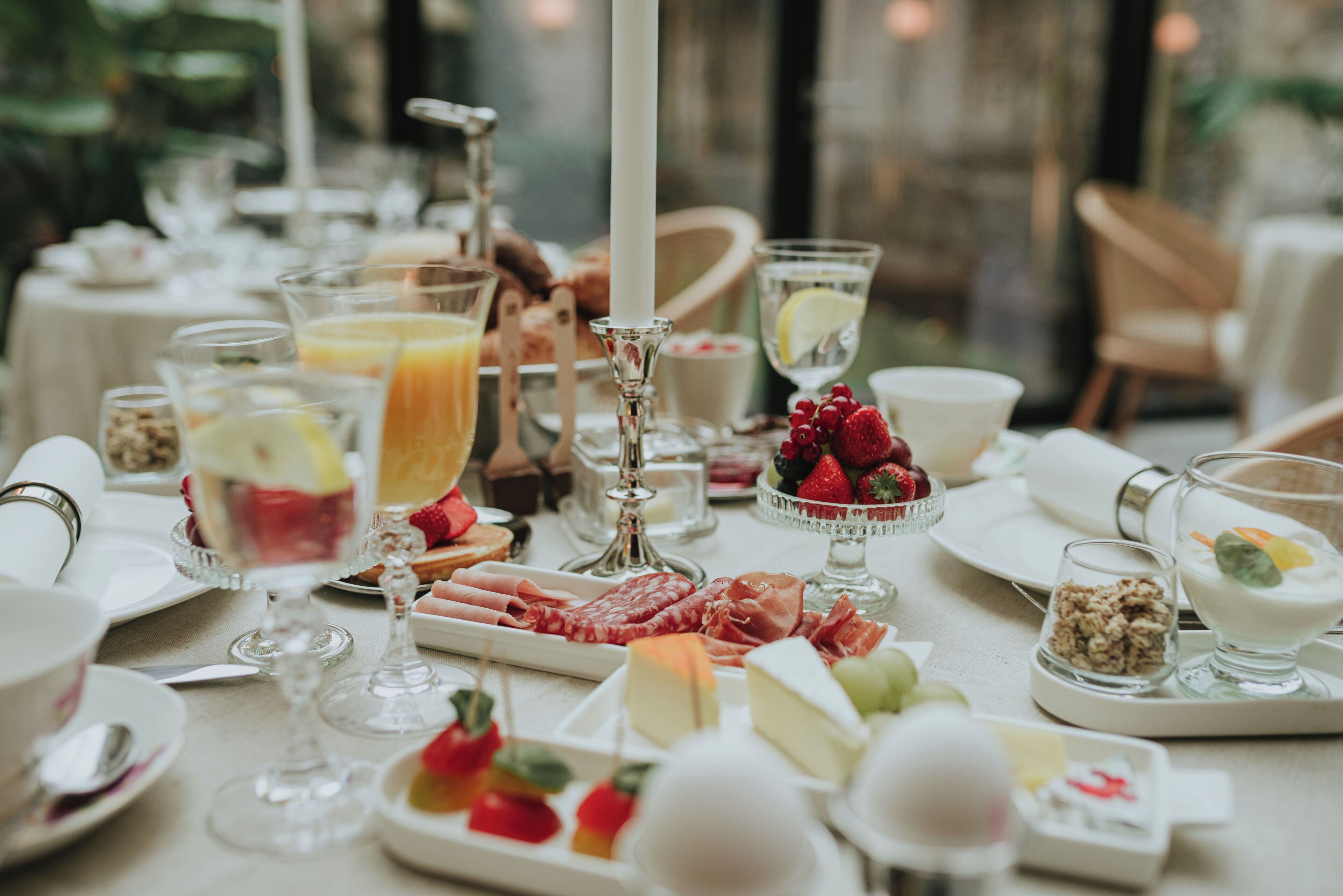 A breakfast buffet with various cheeses, fruits, and beverages.