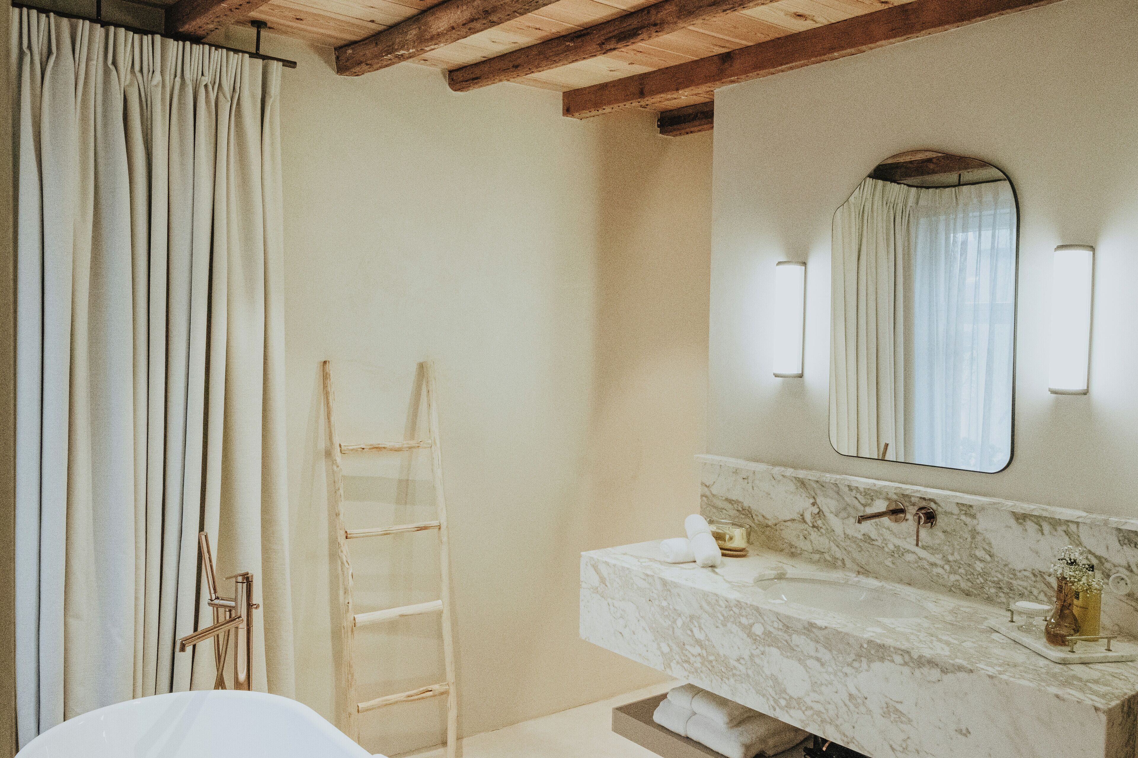 A bathroom with a marble sink, a towel rack, and a wooden ladder.