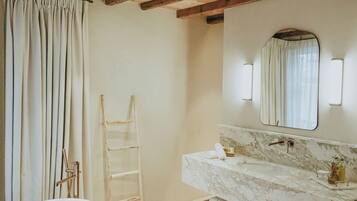A bathroom with a marble sink, a towel rack, and a wooden ladder.