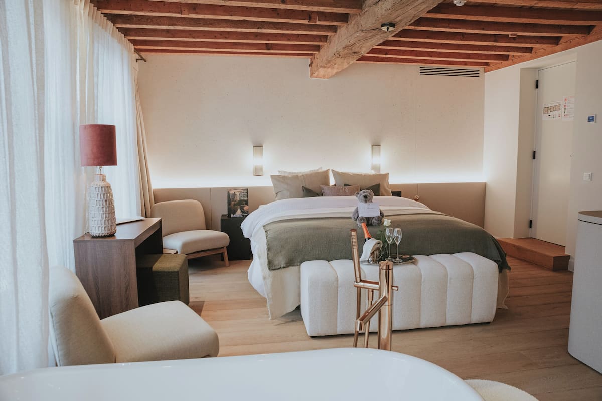 Un dormitorio con cama, mesitas de noche, escritorio, silla y lámpara.