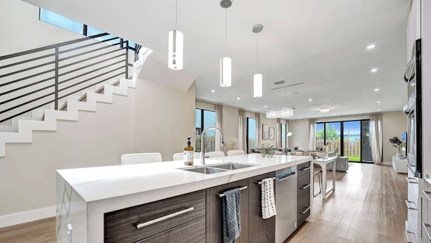 A modern kitchen with a central island, built-in appliances, and a staircase leading to an upper level.