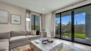 A modern living room with a sofa, coffee table, and large windows.