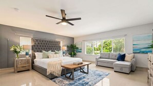 A modern bedroom with a bed, a sofa, a coffee table, and a ceiling fan. - 6 BR Villa Steps to Ocean, Pool, Sauna & Jacuzzi (Fort Lauderdale)