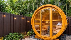 A wooden sauna structure with a circular design, surrounded by a wooden fence, and set in a landscaped garden with tropical plants. - 6 BR Villa Steps to Ocean, Pool, Sauna & Jacuzzi (Fort Lauderdale)