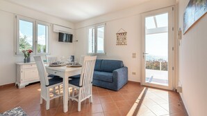 Una cocina moderna con comedor, un sofá azul y vistas a través del ventanal.
