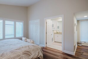 Ein Schlafzimmer mit einem großen Bett, weißen Türen und Blick ins Badezimmer.