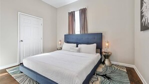 Un dormitorio con cama, ventilador de techo, puerta y una lámpara fijada a la pared.
