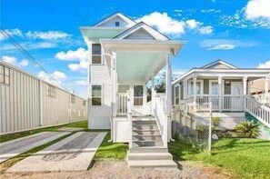 Une maison à deux étages avec un porche à l’avant et un escalier extérieur abrité.