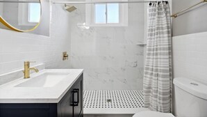 A bathroom with a white sink, gold faucet, and a shower with a patterned curtain.