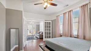 A bedroom with a bed, a ceiling fan, and a view of a hallway.
