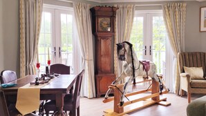A dining area with a wooden table, chairs, and a decorative horse sculpture. - 'Pepperpot' Lodge on Isis & Windrush Lakes with Great On-site Facilities (South Cerney)