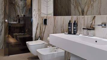 Un baño moderno con un espejo grande, paredes de mármol y un bidé.