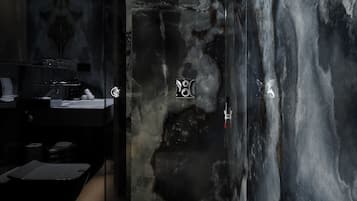 Een moderne badkamer met een grote spiegel, donkere marmeren wanden en een strak zwart aanrecht.