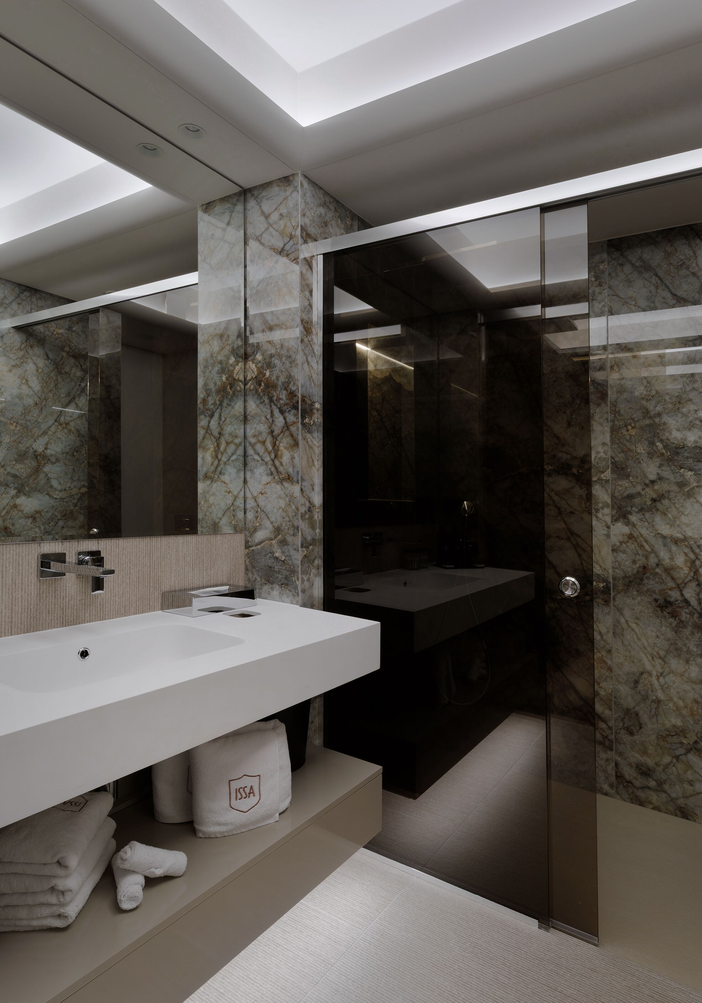A modern bathroom with a large mirror, a white sink, and a glass shower enclosure.