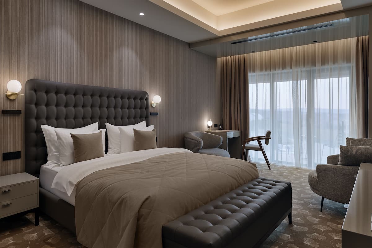Ein modernes Hotelzimmer mit einem großen Bett, einer Sitzecke und Blick auf die Stadt.