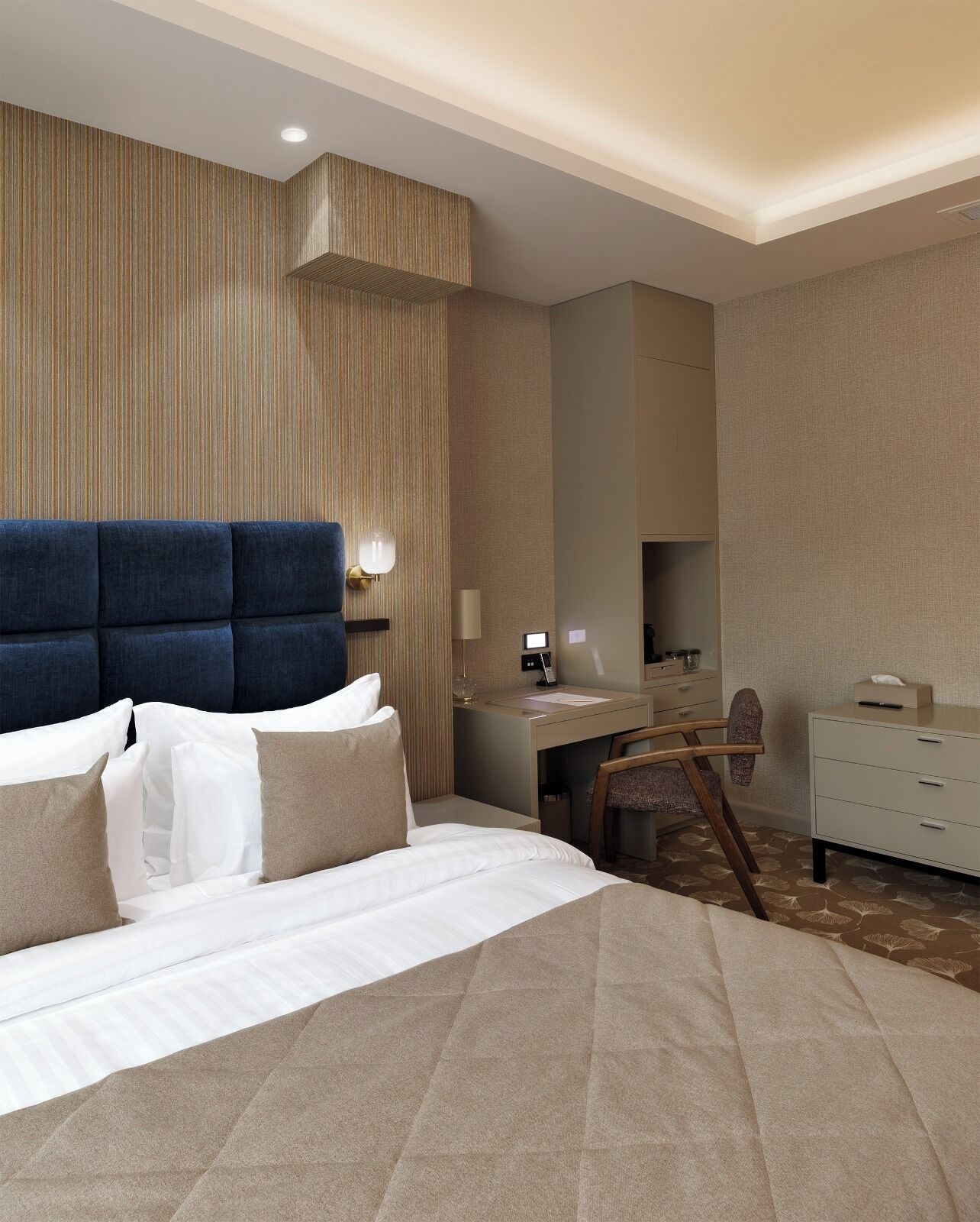 Una habitación de hotel moderna con una cama grande, un escritorio y una silla.