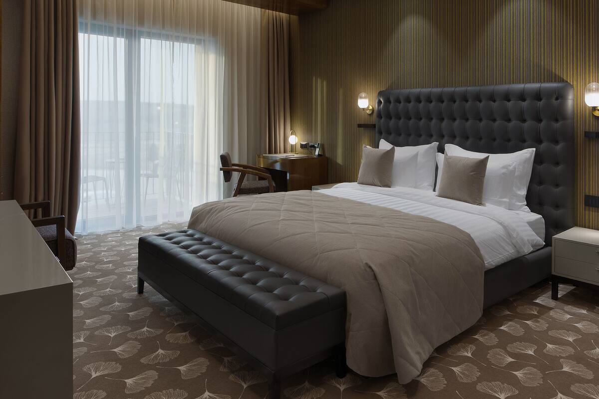 Ein modernes Hotelzimmer mit einem großen Bett, einem Schreibtisch und einer Sitzbank.