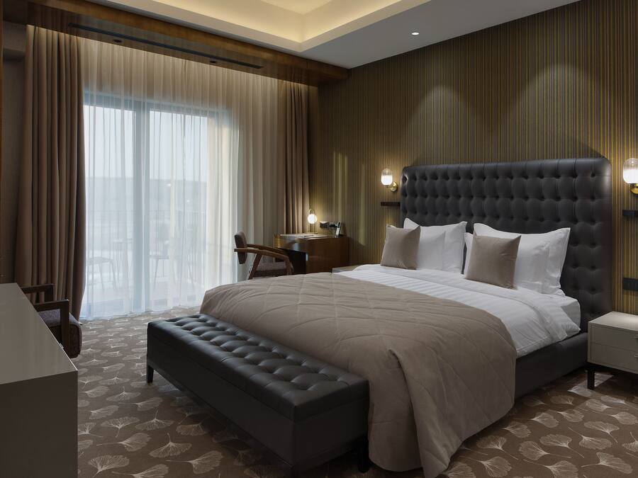 Una habitación de hotel moderna con una cama grande, un escritorio y un banco.