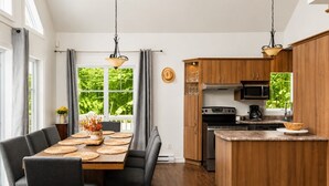 Una cocina moderna con armarios de madera, una isla central y un comedor con mesa dispuesta para cuatro.