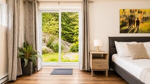 Un dormitorio con cama, mesita de noche, lámpara y un cuadro.