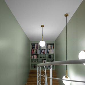 A room with a staircase, a bookshelf, and pendant lights.