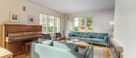 Una sala de estar con un piano, un sofá, una mesa de centro y una chimenea.