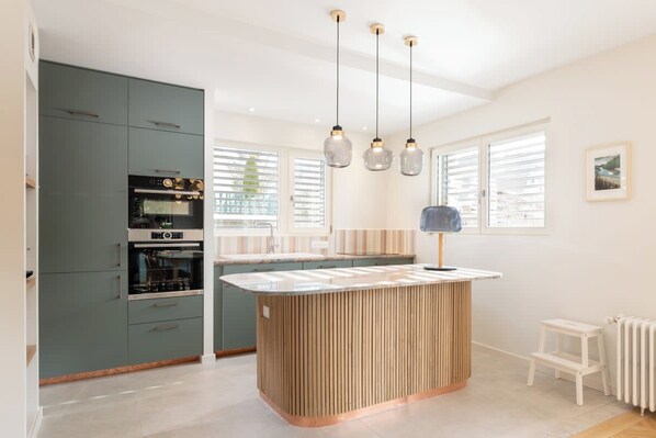A modern kitchen with a central island, built-in appliances, and pendant lighting.