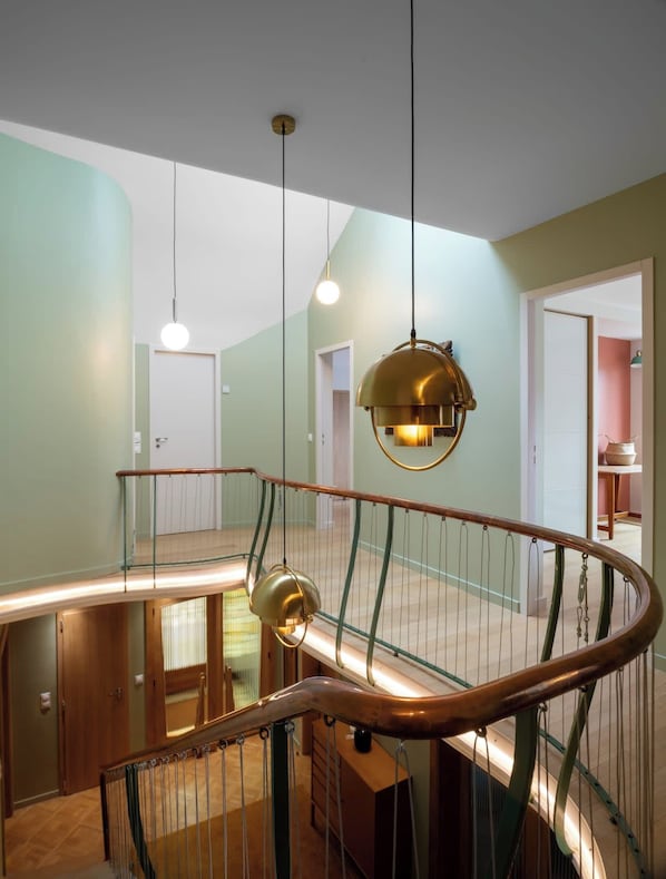 A modern interior with a curved staircase, pendant lighting, and a view of adjacent rooms.