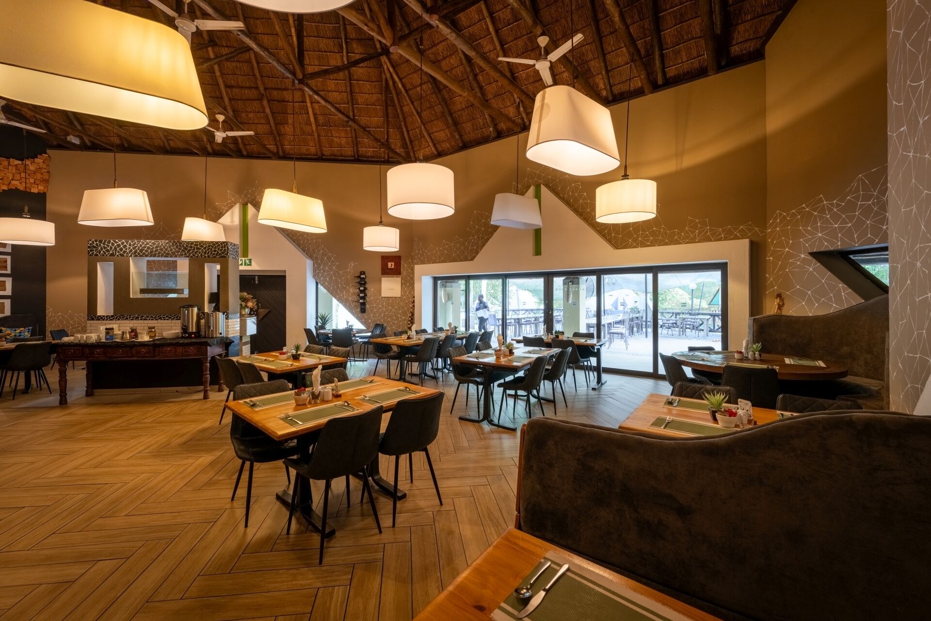 A spacious restaurant with high ceilings, large windows, and modern lighting fixtures.