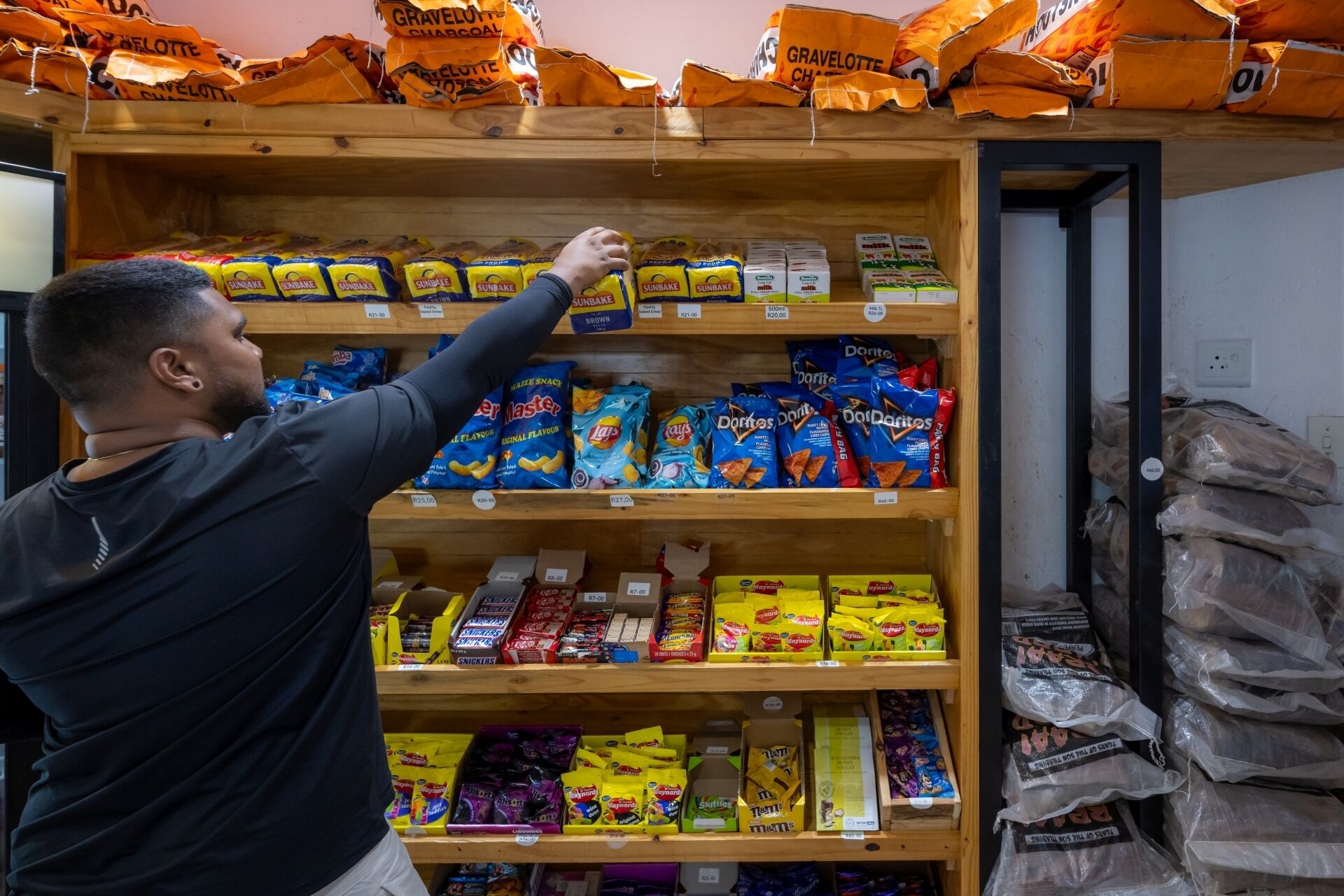 A person reaching for a snack on a shelf stocked with various packaged goods.