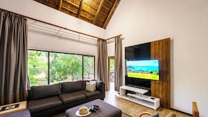 A living room with a large TV, a sofa, a coffee table, and a chair. - First Group Sanbonani Resort (Mbombela)