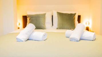 A hotel room with a neatly made bed, two pillows, and two bedside lamps.