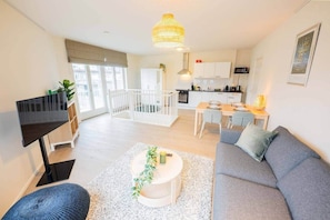 A modern apartment with a living room, dining area, kitchen, and balcony.