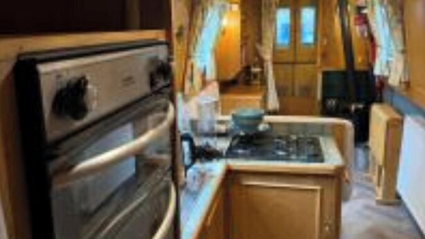 A compact kitchen with a double oven, a stove, and wooden cabinets. - Narrowboat in Birmingham City (Birmingham)