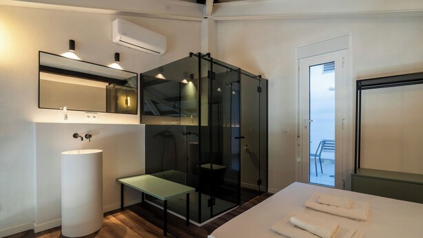 A modern bathroom with a glass shower enclosure, a white sink, and a bench. - VLC Host - Reina  (Valencia)