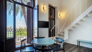 A modern interior with a round table and chairs, a staircase, and a view of palm trees outside. - VLC Host - Reina  (Valencia)
