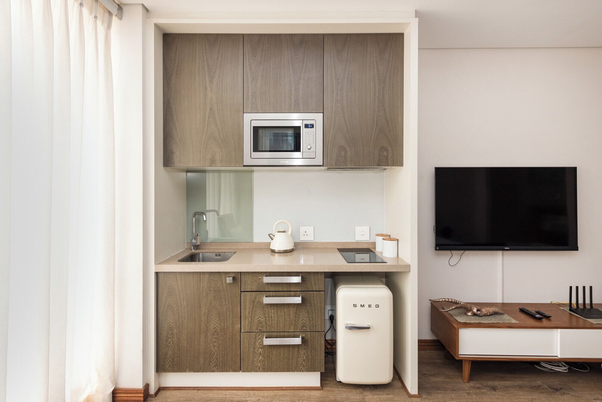 Una kitchenette compacta con microondas, pileta y pequeño refrigerador.