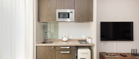 Una kitchenette compacta con microondas, pileta y pequeño refrigerador.