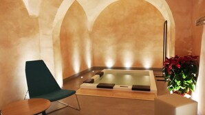 Une salle de spa équipée d’une table de massage, d’un fauteuil de massage et d’une petite table.