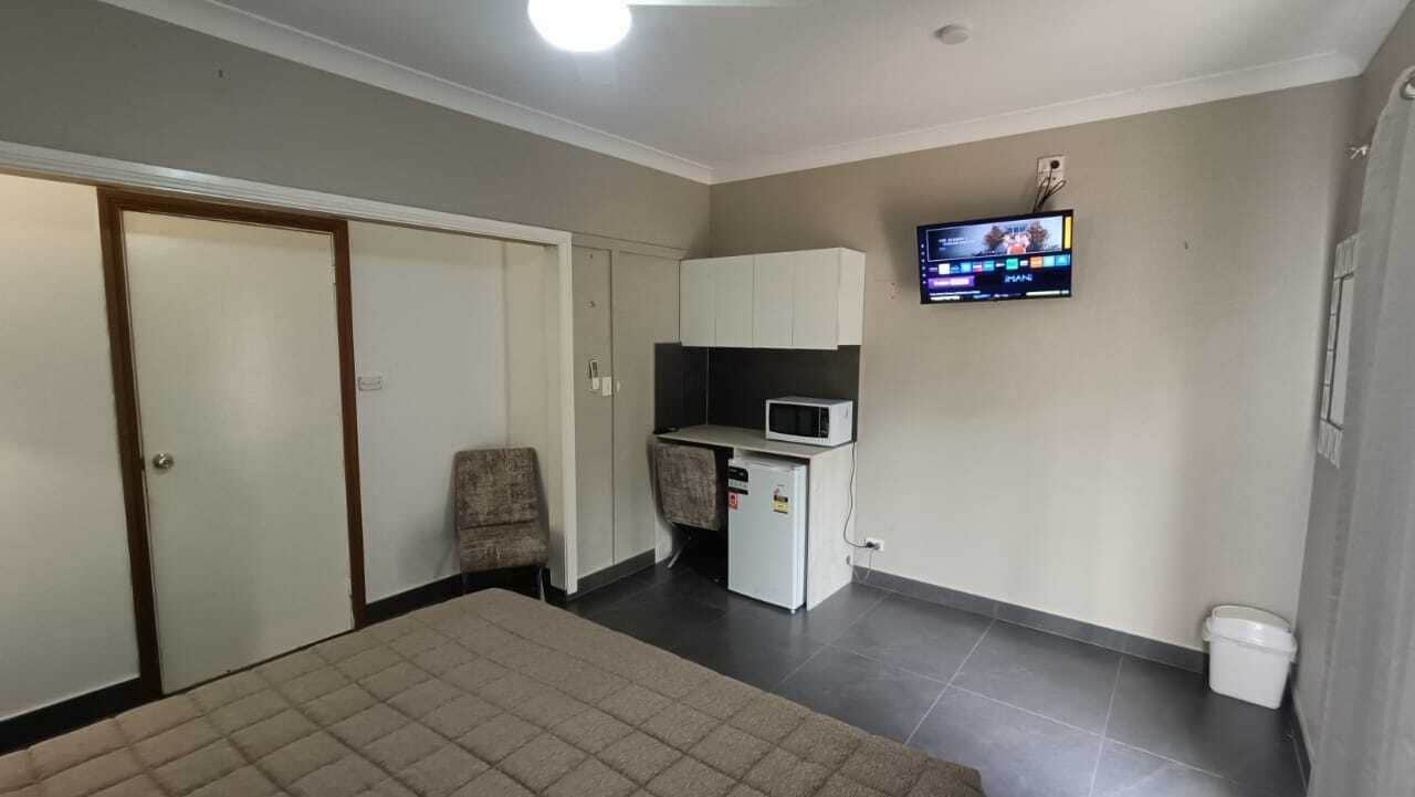 Une chambre comprenant un lit, un bureau avec un micro-ondes, une télévision et une armoire.