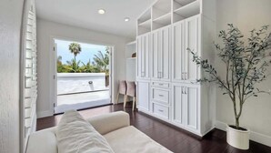 A spacious room with a large white wardrobe, a comfortable sofa, and a potted plant. - Luxury Sanctuary Retreat-Heated pool-Hot tub-Volleyball (Encinitas)