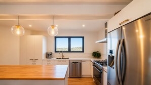 A modern kitchen with a stainless steel refrigerator, a built-in oven, and a coffee machine.